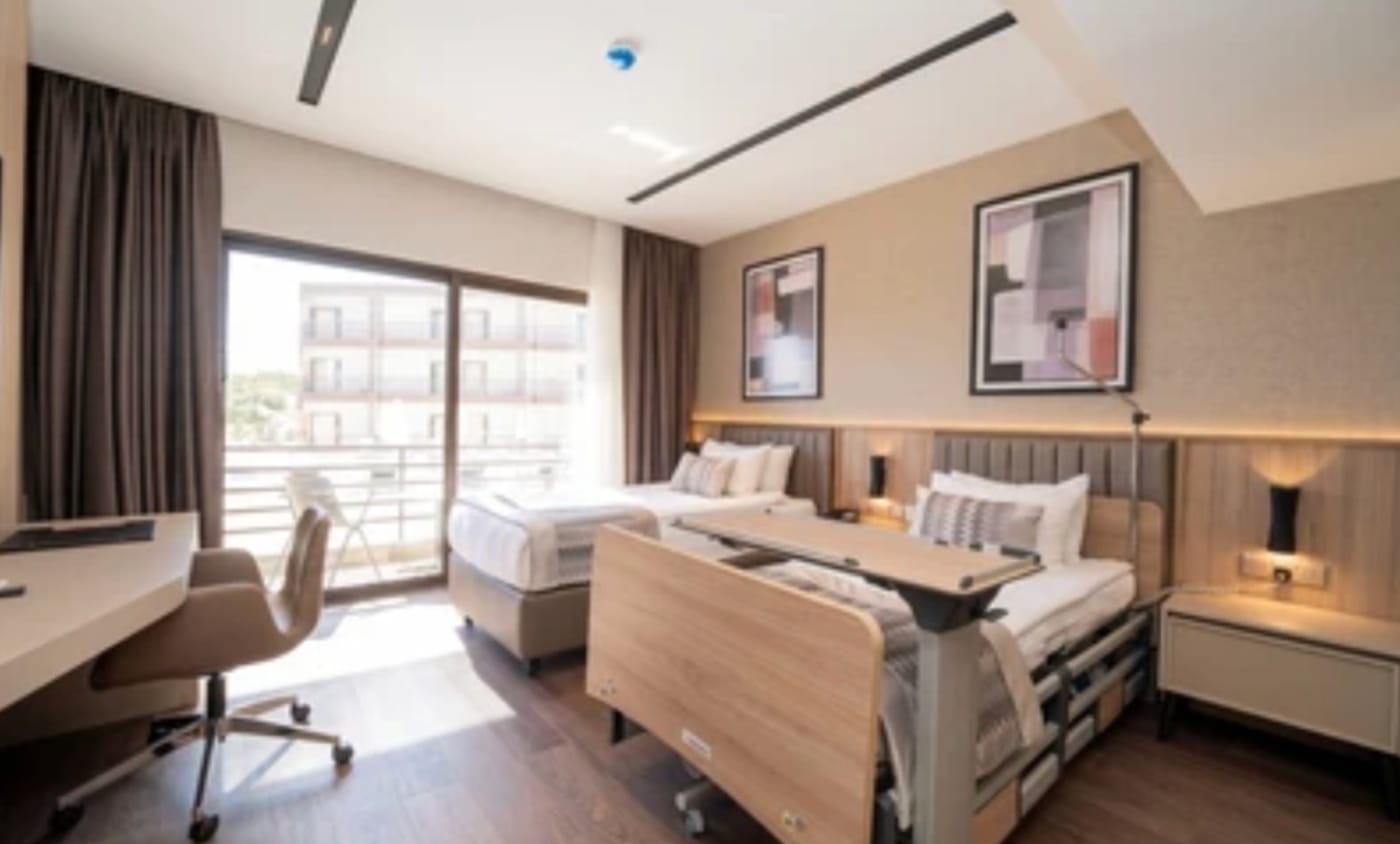 An accessible patient room with a medical bed, a companion bed and a balcony