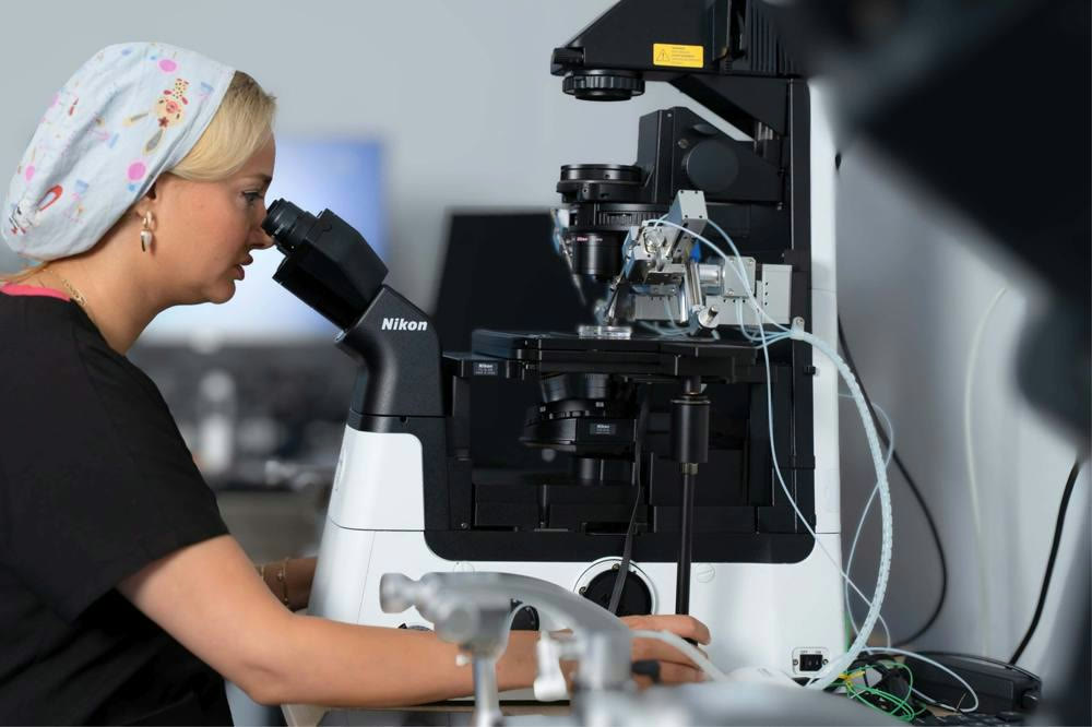 An embryologist at SAGA Clinic looking through a laboratory microscope