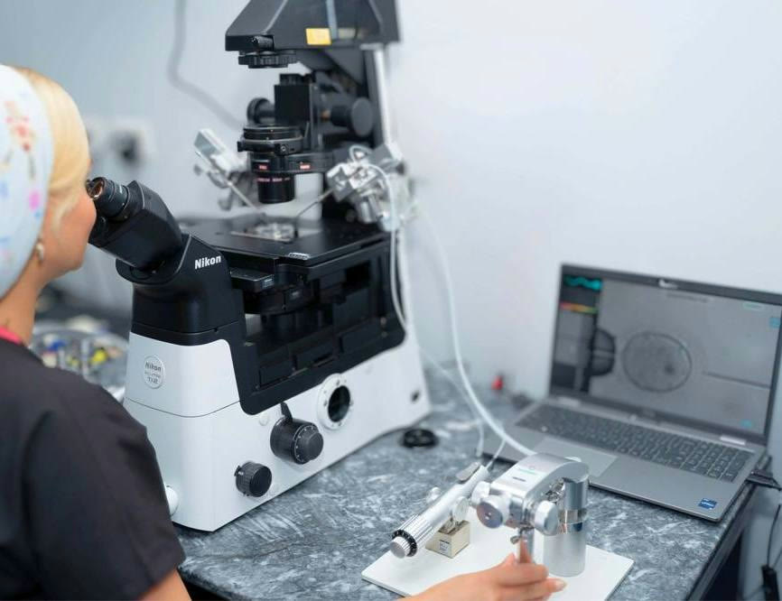 An embryologist at SAGA Clinic working at an ICSI micromanipulation microscope